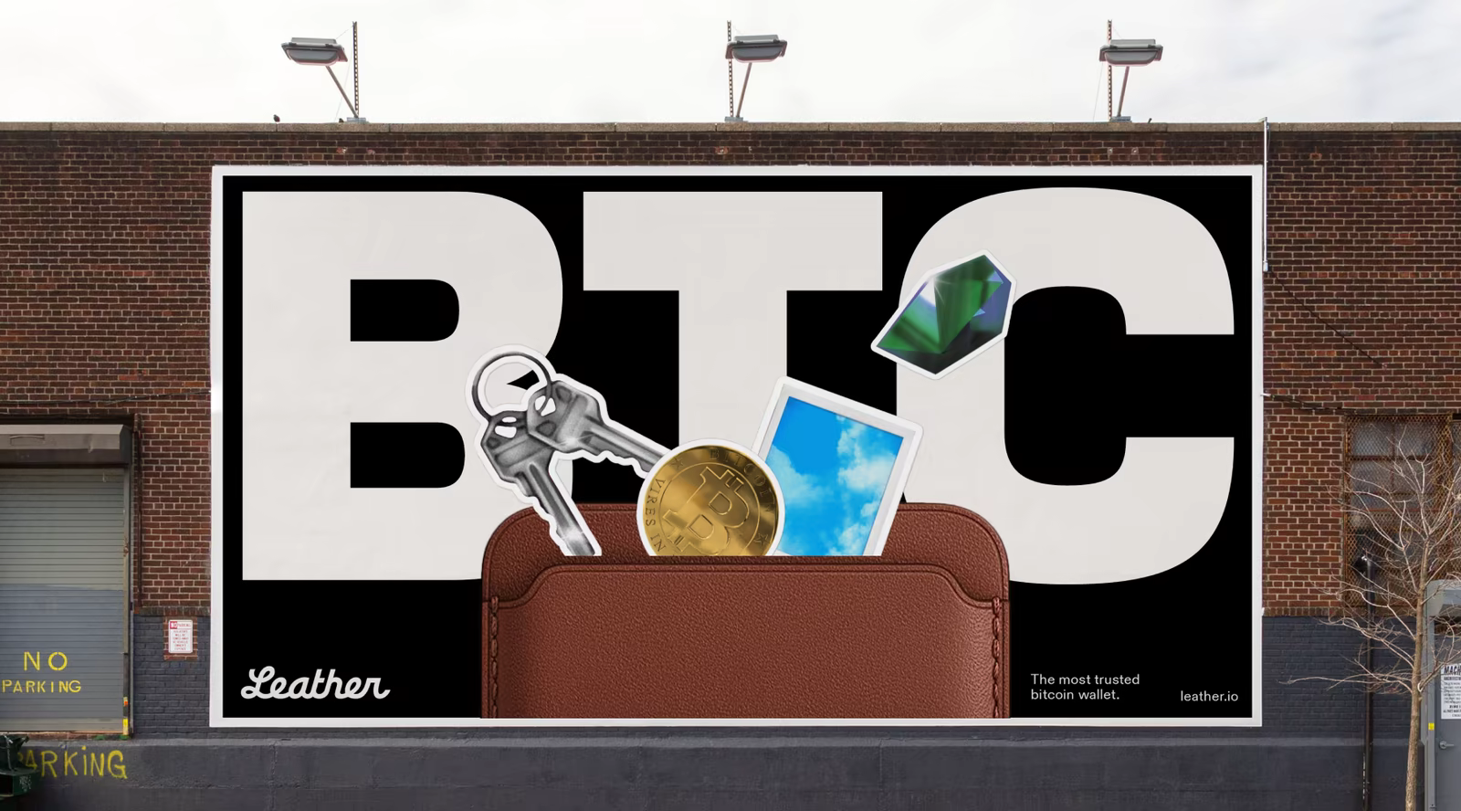 A billboard on a brick wall reading BTC, with keys, a coin and a photo tucked into a leather wallet